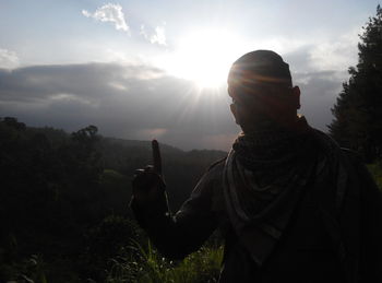 Silhouette of man with arms raised against sun