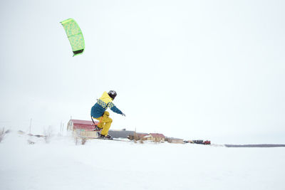 Man with umbrella on snow against sky