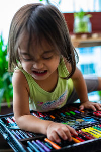 Close-up of angry girl looking at crayons on table