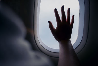 Cropped hand of woman touching airplane window