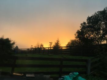 Trees on landscape against clear sky during sunset