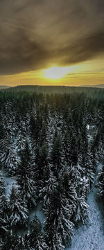 Scenic view of snow covered land against sky at sunset