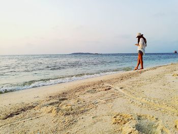 Woman standing on beach against sky