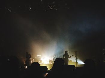 Silhouette people photographing at music concert against sky at night