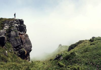 Woman standing on cliff during foggy weather
