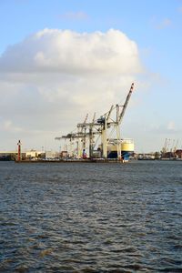 Cranes at commercial dock against sky