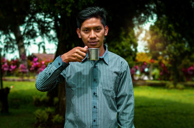 Portrait of young man standing against plants