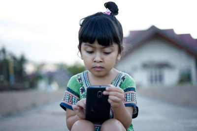 Girl using phone while sitting on land