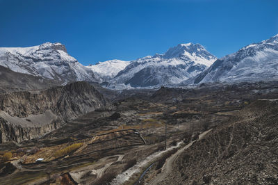 Scenic view of snowcapped mountains against blue sky