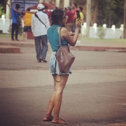 Rear view of woman photographing on city street