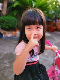 Portrait of cute girl with finger on lips sitting on bicycle