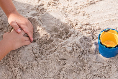 High angle view of person hand playing with sand at beach