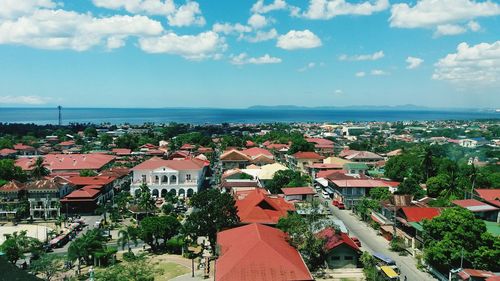 Aerial view of city by sea against sky