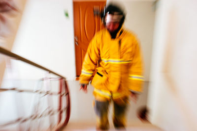 Blurred motion of man standing against yellow wall