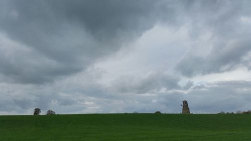 Scenic view of grassy field against cloudy sky