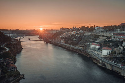 River amidst buildings against sky during sunset