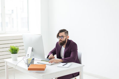 Young man using mobile phone while sitting on table