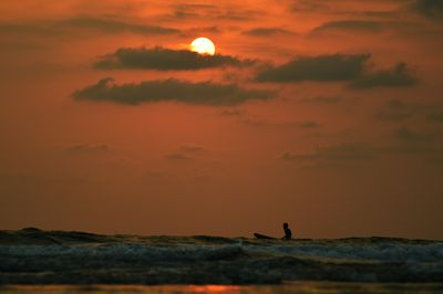 Silhouette of surfer at sunset