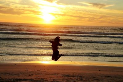 Silhouette person on beach against sky during sunset