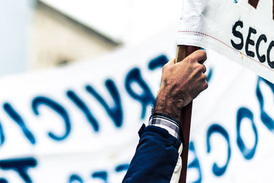 Close-up of hand holding text against wall