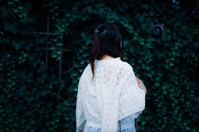 Rear view of woman standing against trees