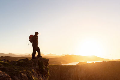 Man standing on mountain against sky during sunset