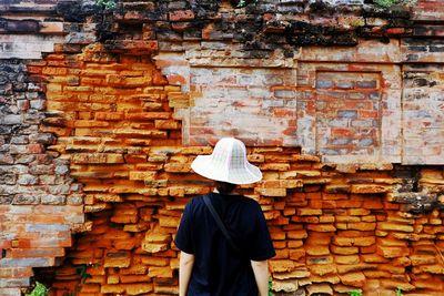 Midsection of woman with umbrella on brick wall