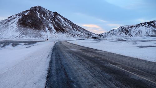 Road amidst snowcapped mountains against sky