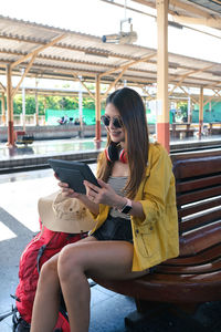 Young woman using phone while sitting on laptop