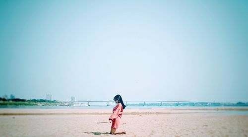 Full length of woman on beach against clear sky