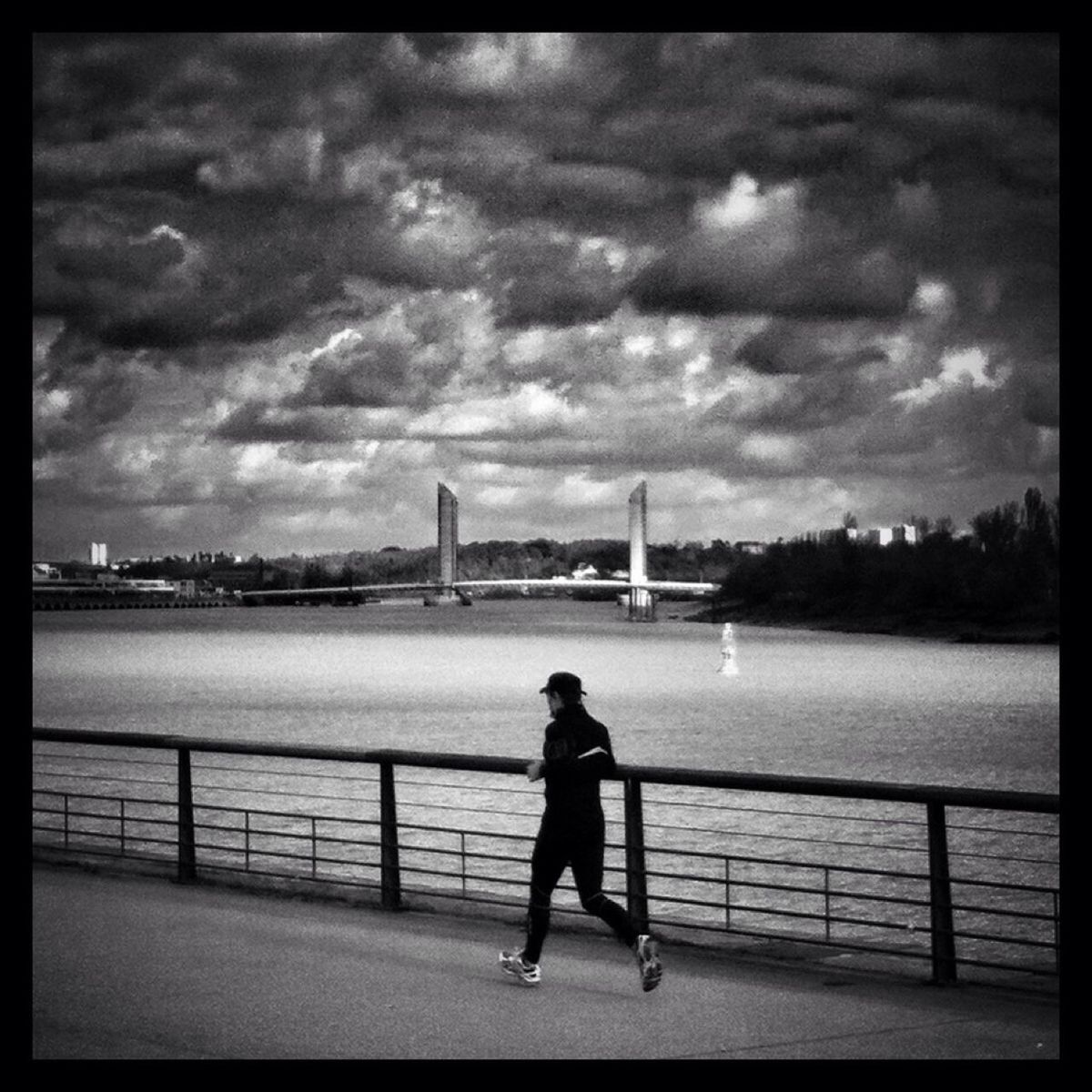 sky, water, full length, cloud - sky, rear view, railing, transfer print, standing, architecture, river, built structure, cloudy, building exterior, cloud, auto post production filter, city, lifestyles, leisure activity