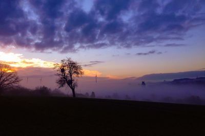 Scenic view of silhouette field against sky at dusk