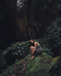 Woman sitting on rock in forest