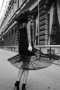 Rear view of woman with umbrella standing on street