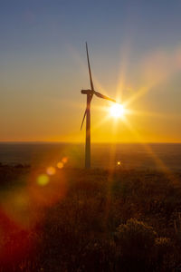 Wind turbines on field during sunset