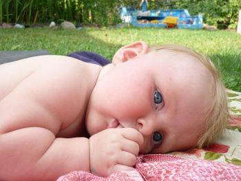 Close-up portrait of cute baby girl lying on picnic blanket 