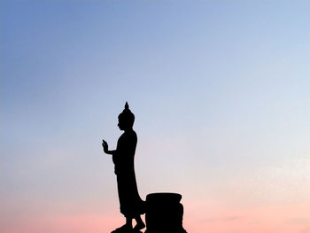 Silhouette buddha statue against sky during sunset