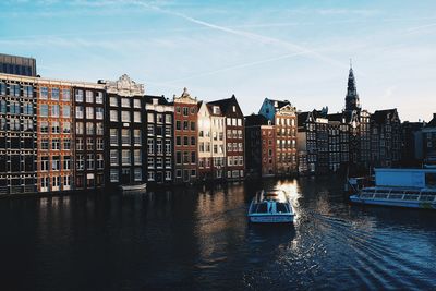 Buildings by river against sky in city