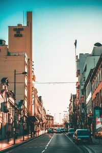 Road by buildings against sky in city
