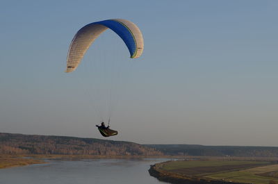 Man paragliding over sea against clear sky