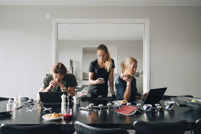 Family using technologies at dining table in room