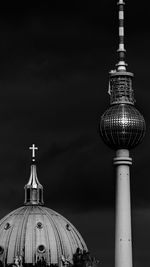 Low angle view of communications tower in city against sky