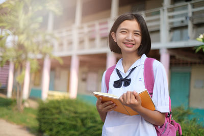 Portrait of smiling teenage girl standing outdoors