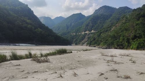 Scenic view of river by mountains against sky