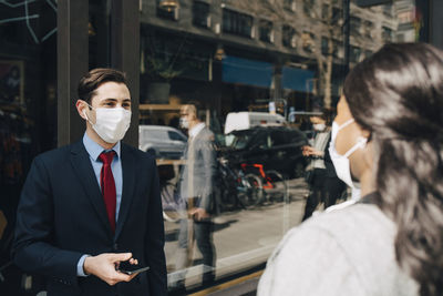 Businessman in face mask talking with female colleague during pandemic