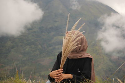 Woman holding flowers against mountain