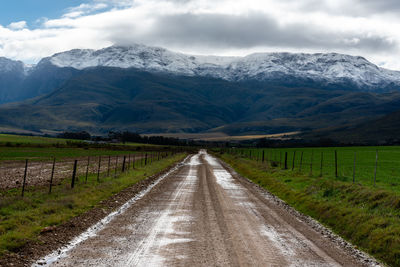 Road amidst snowcapped mountains against sky