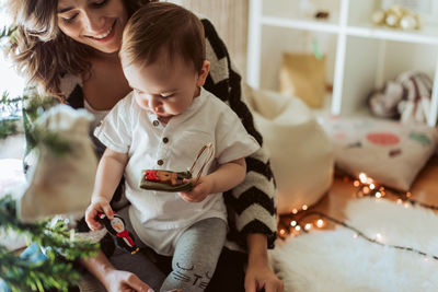 Rear view of mother and daughter holding baby at home