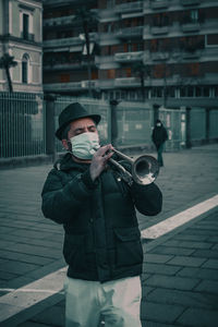 Man wearing hat standing on street in city