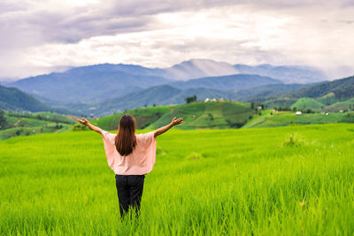 Rear view of woman walking on field